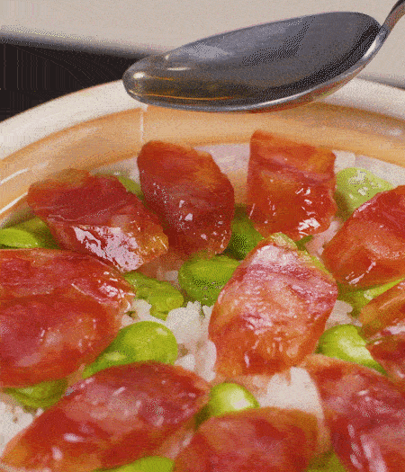 大米出現(xiàn)小孔時(shí)開蓋放香腸，往鍋邊淋入少許油，再燜煮8~10分鐘左右。